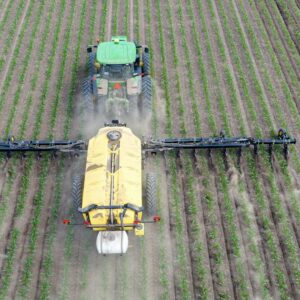Machine agricole épandant de l'engrais azoté sur une culture, illustration de la filière des fertilisants